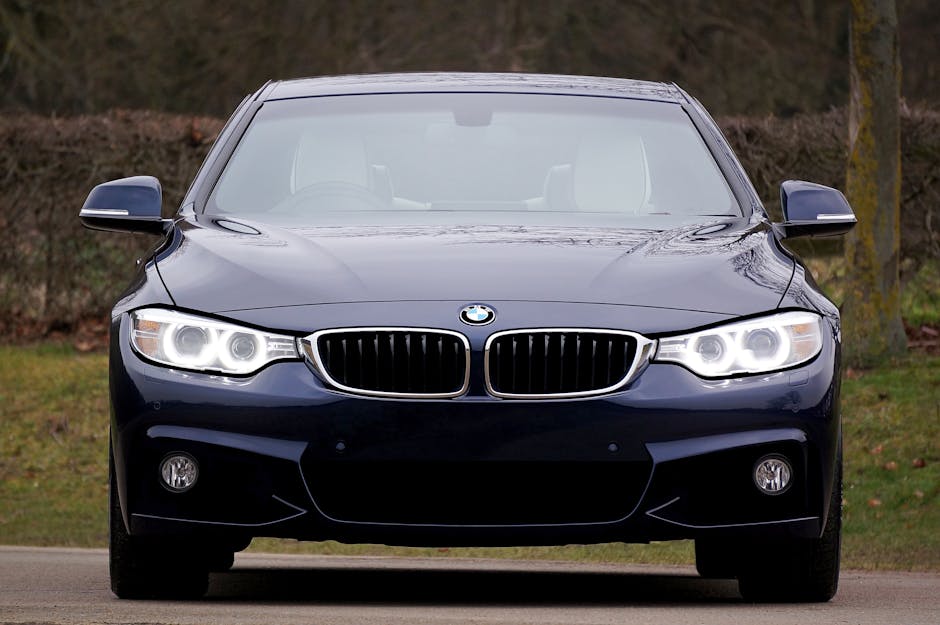 A sleek, blue luxury sedan car with illuminated headlights, emphasizing elegance and modern design.